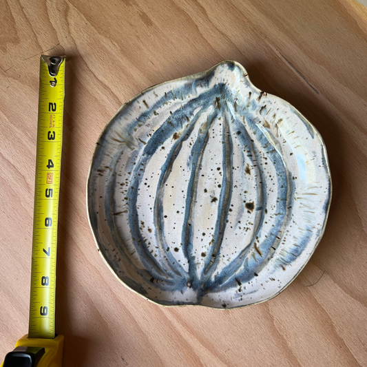 Ceramic pumpkin dish with blue patterns next to a yellow measuring tape on a wooden surface