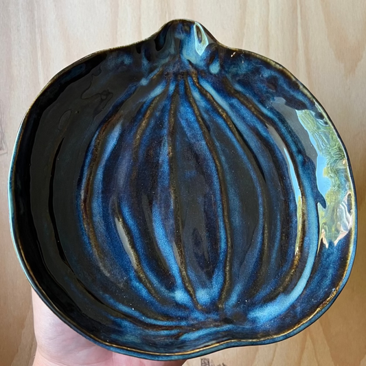 Blue ceramic bowl held in a hand on a wooden surface
